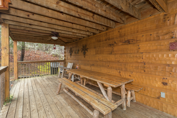 Picnic table on a covered deck at Alpine Romance, a 2 bedroom cabin rental located in Pigeon Forge