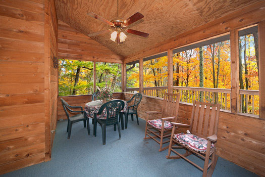 Screen porch with patio table and rockers at Raccoon's Rest, a 2 bedroom cabin rental located in Pigeon Forge