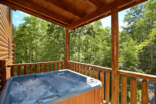 Covered deck with hot tub at Pool House, a 2 bedroom cabin rental located in Gatlinburg