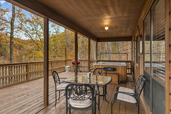 Hot tub and dining table for four on the covered deck at Papa Bear, a 3 bedroom cabin rental located in Pigeon Forge