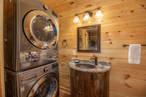 Stacked washer and dryer in a bathroom with a custom sink at Elk Horn Lodge, a 5 bedroom cabin rental located in Gatlinburg