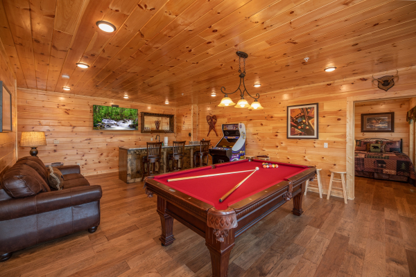 Red felt pool table, arcade game, and bar in the game room at Elk Horn Lodge, a 5 bedroom cabin rental located in Gatlinburg