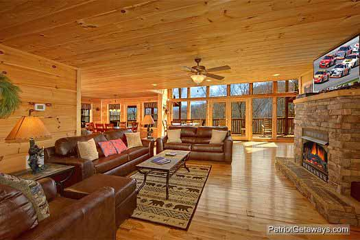 Looking at the sofas in the living room with dining open along the back at Alpine Pointe, a 5 bedroom cabin rental located in Gatlinburg