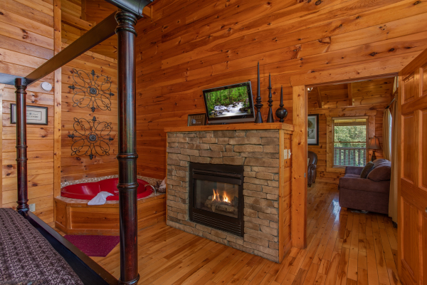 Fireplace and tv in the bedroom next to the jacuzzi at Majestic Sunrise, a 1 bedroom cabin rental located in Pigeon Forge