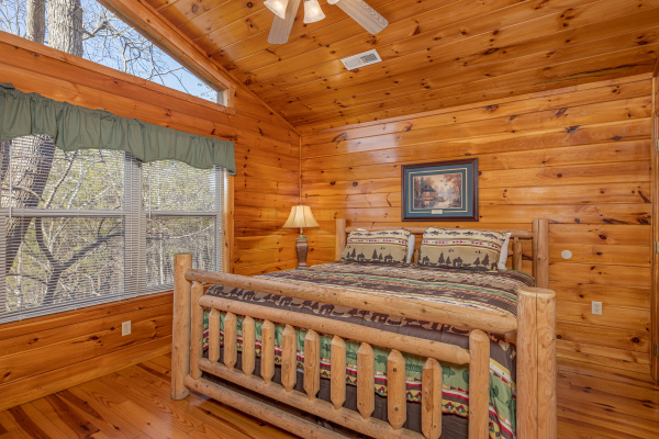 Loft bedroom with a king log bed, night stand, and lamp at Hickernut Lodge, a 5-bedroom cabin rental located in Pigeon Forge