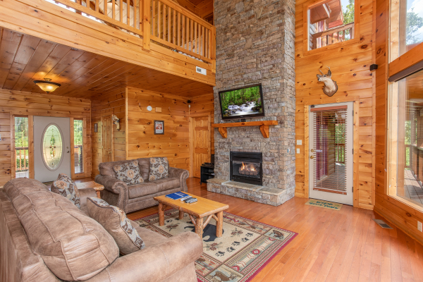 Vaulted living room with tall fireplace and deck access at Four Seasons Lodge, a 3-bedroom cabin rental located in Pigeon Forge