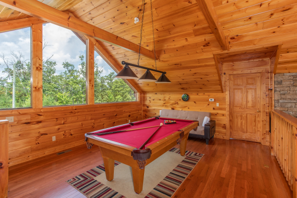 Red felt pool table in the game loft at Four Seasons Lodge, a 3-bedroom cabin rental located in Pigeon Forge