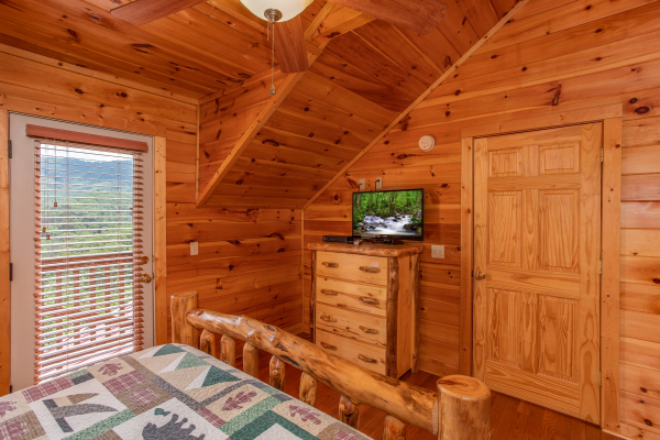 Queen bedroom with deck access, a dresser, and TV at Four Seasons Lodge, a 3-bedroom cabin rental located in Pigeon Forge